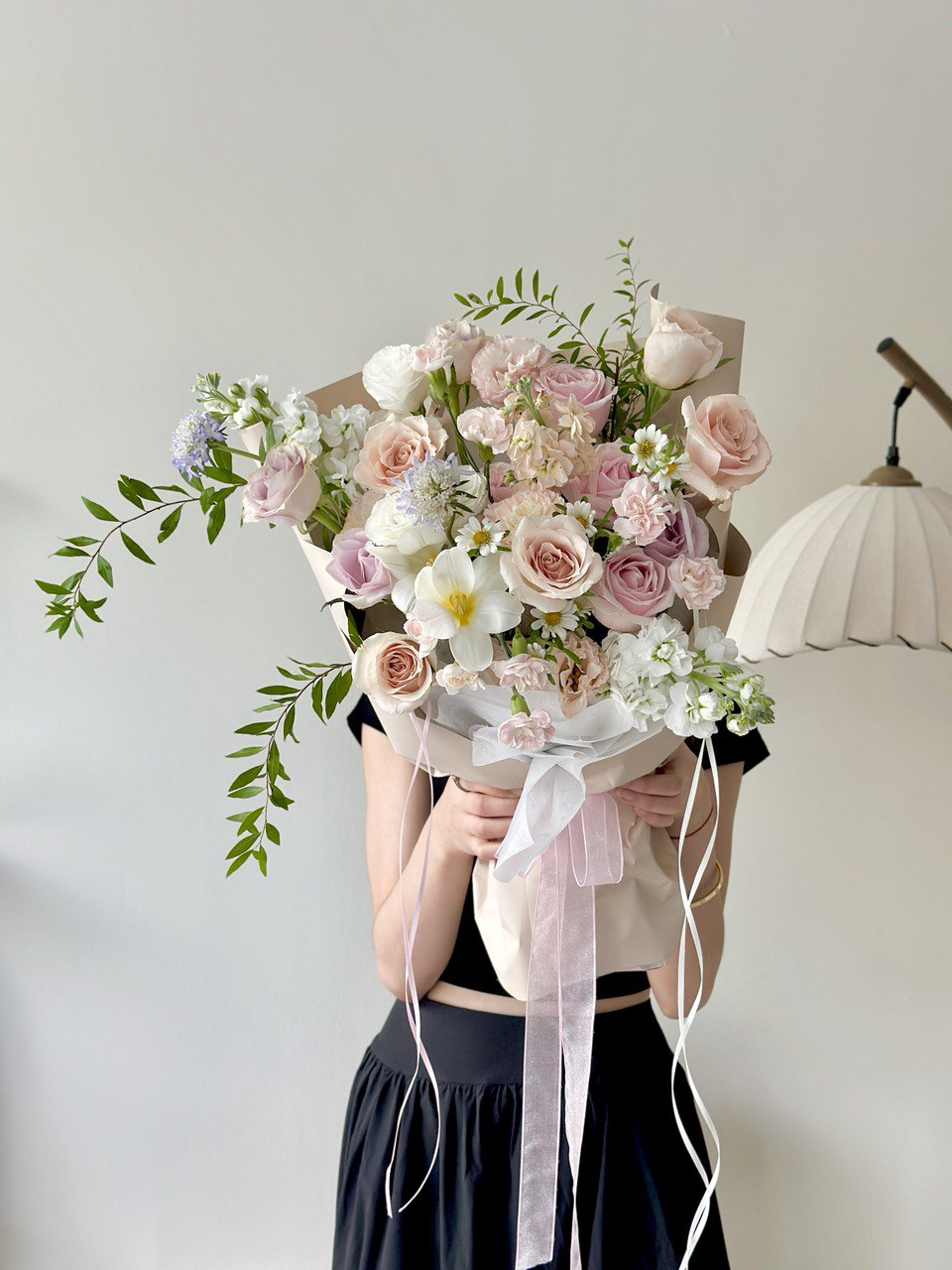 Person holding a bouquet of flowers against a plain background. Perfect for birthday or anniversaries.