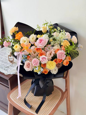 Luxury floral arrangement with orange, yellow, and pink blooms for birthday or anniversary gifts.