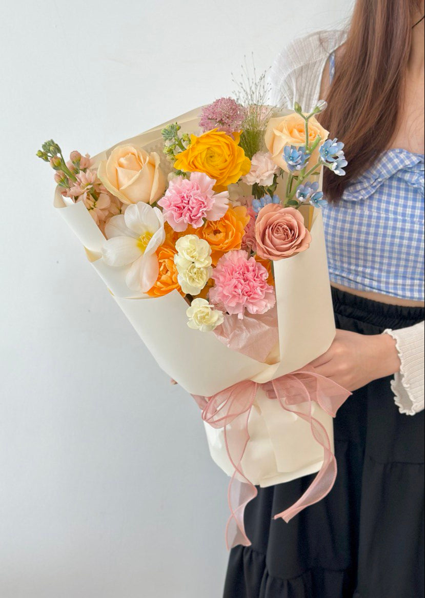 A girl in a blue top holds a colorful bouquet of flowers for her mother on Mother's Day 2025.
