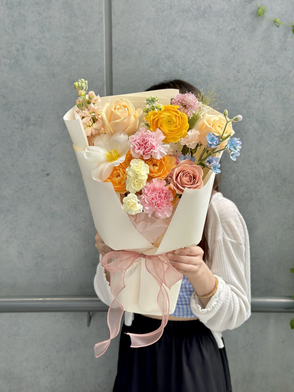 A young girl wearing a blue top presents a vibrant bouquet of flowers to her mother for Mother's Day 2025.