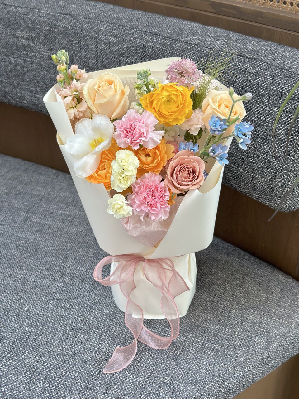 A bouquet of colourful flower is placing on a grey chair for a photoshoot for Mother's Day flower.