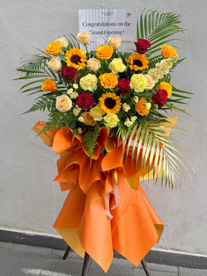 Floral arrangement with orange ribbon and 'Congratulations on the Grand Opening!' card against a gray background perfect for grand opening flower stand gift prepared by hug and heart florist at Sunway Geo.