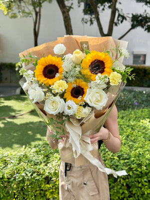 Close-up of a sunflower-themed bouquet, accented with white and yellow blooms, perfect for celebration or a cheerful gift.