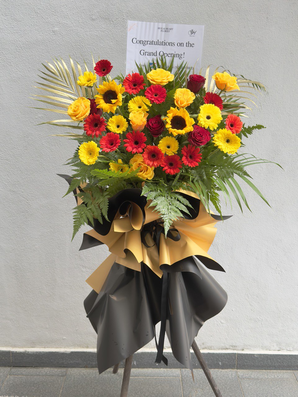 A grand opening flower stand with 'Congratulations on the Grand Opening' card against a gray background with delivery at Kuala Lumpur.