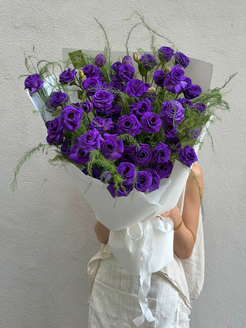 A bouquet of purple Eustoma wrapped in white wrapper ideally for birthday or anniversaries celebration at Kuala Lumpur.