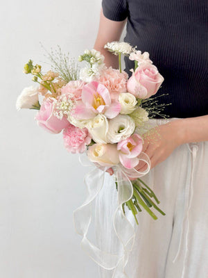 A woman holds a bouquet of pink tulips mixed with white and pink roses on her wedding day in Malaysia.