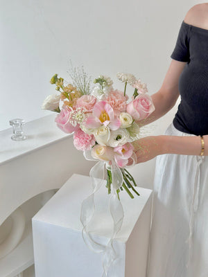 A woman at her wedding in Malaysia holds a bouquet of pink tulips and white roses.