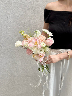 A bride in Malaysia holds a bouquet of pink tulips mixed with white and pink roses, celebrating her wedding day.