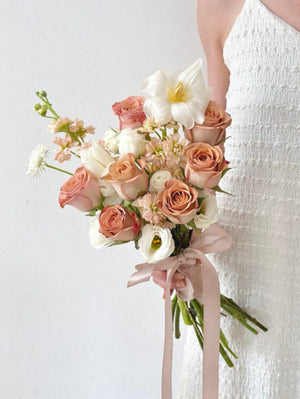 A woman in a white dress holds a bouquet of Cappuccino Rose flowers, celebrating her wedding in Kuala Lumpur.