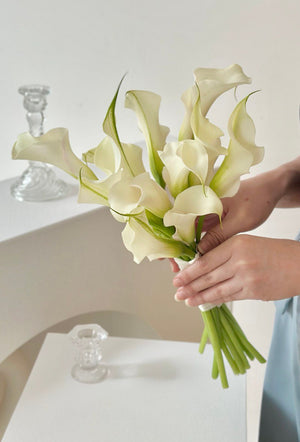 1. A bride holding a bouquet of white calla lilies, symbolizing elegance and purity for her ROM wedding ceremony.
2. A woman in a wedding dress holds a bouquet of white calla lilies, representing grace and beauty for her ROM wedding.
3. A bride proudly displays a bouquet of white calla lilies, chosen for their elegance for her ROM wedding celebration.