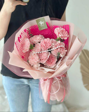 A girl is wearing black T shirt is holding a bouquet of carnation for her mother during mother's day.