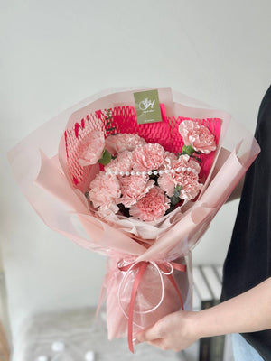 A girl is wearing black T shirt is holding a bouquet of carnation for her mother during mother's day.