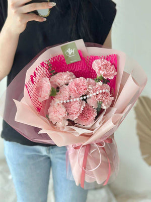A girl is wearing black T shirt is holding a bouquet of carnation for her mother during mother's day.