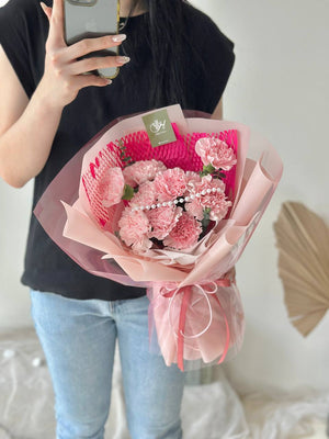 A girl is wearing black T shirt is holding a bouquet of carnation for her mother during mother's day.