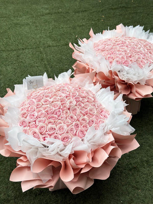 A bouquet of proposal pink roses arranged in a specific formation to symbolize a number, placed on a green background.