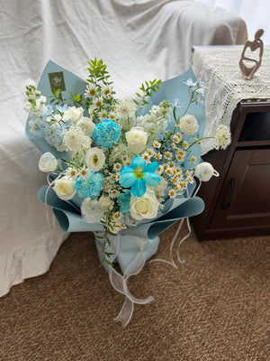 Bouquet of blue and white flowers on a surface with a neutral background.
