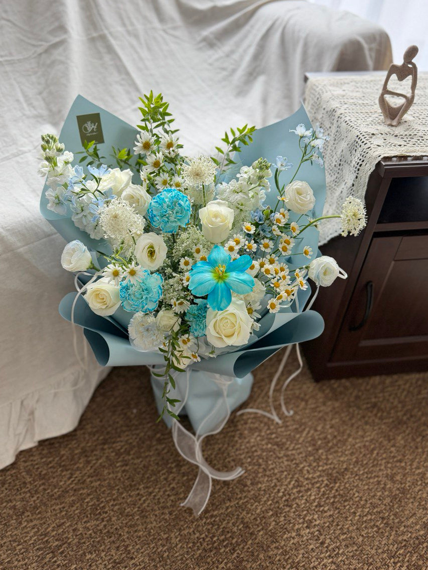 Bouquet of blue and white flowers on a surface with a neutral background.