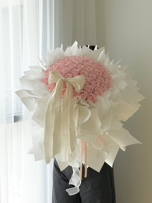 A large bouquet of pink roses wrapped in white wrapper with a cream satin bow, perfect for proposal flower gift.