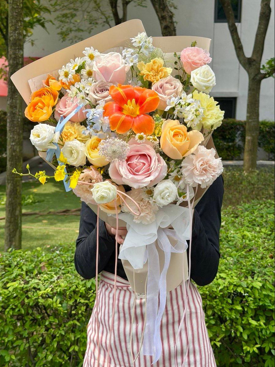 Person holding a large bouquet of flowers outdoors with greenery in the background。