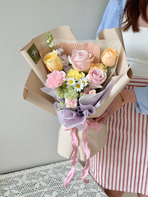 A girl is holding a small bouquet of pastel flower perfect for birthday, anniversaries or just because flower gift.