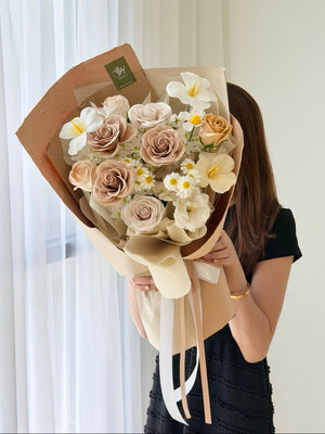 A girl wearing black is holding a bouquet of cappuccino rose soap flower. Long lasting flower.