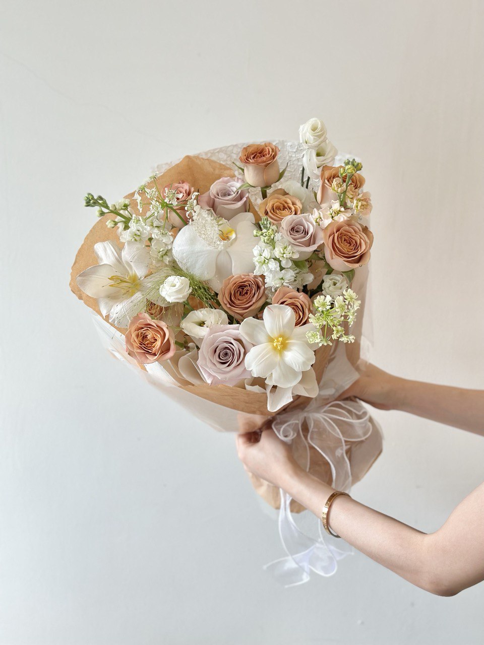A girl in a black dress presents a large bouquet of cappuccino roses at her birthday celebration in Kuala Lumpur.