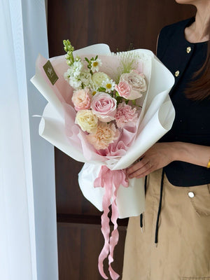 A girl wearing black top is holding a bouquet of pink roses with mixed filler perfect for birthday flower and same day flower delivery at Kuala Lumpur and Selangor.