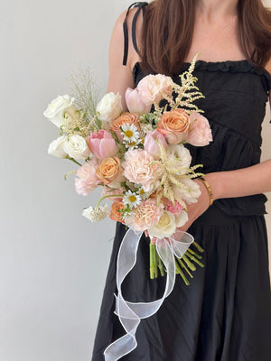 Elegant ROM bouquet in soft pastel shades of peach, pink, and ivory with astilbe and pink tulip.