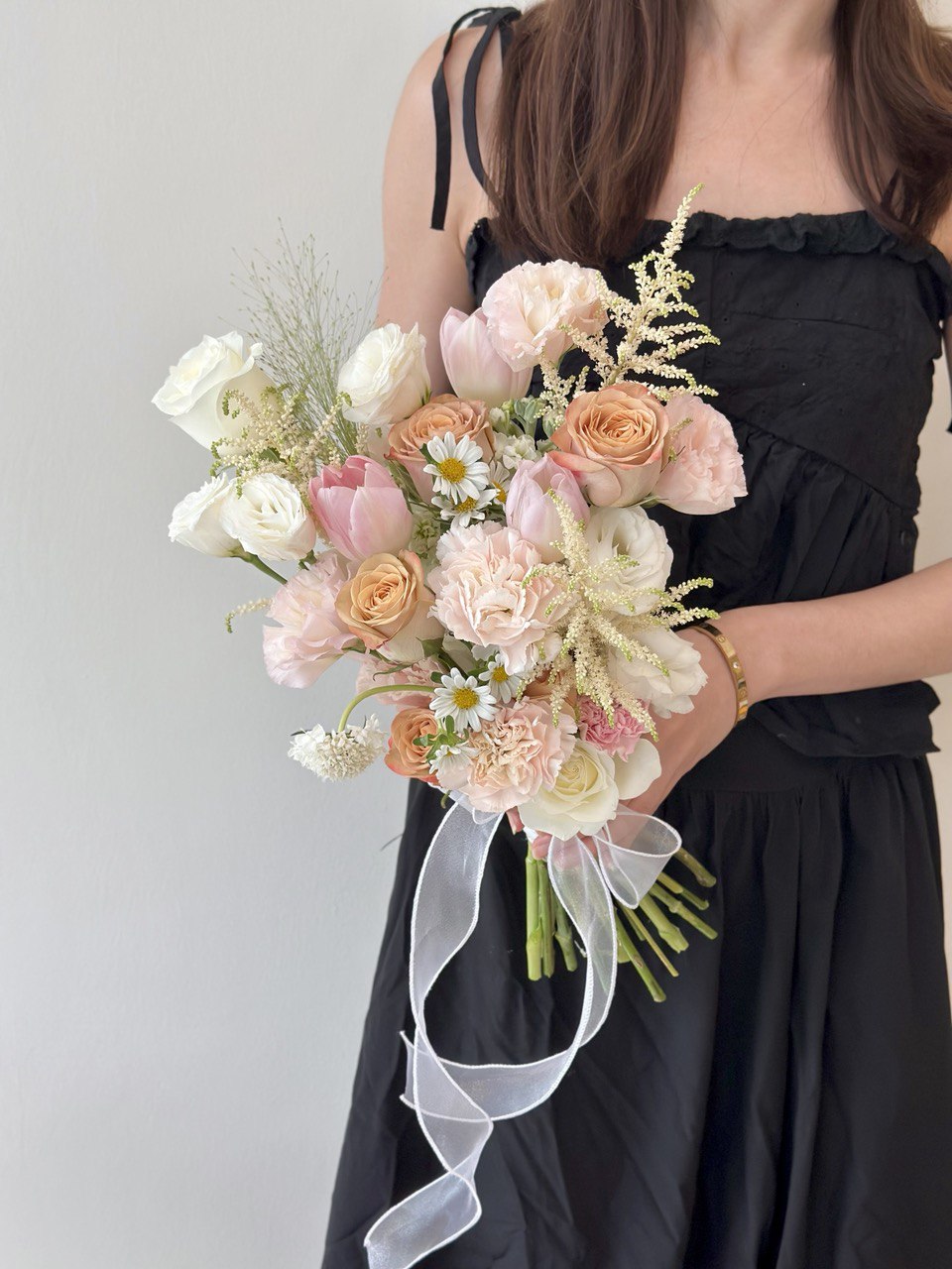 Elegant ROM bouquet in soft pastel shades of peach, pink, and ivory with astilbe and pink tulip.