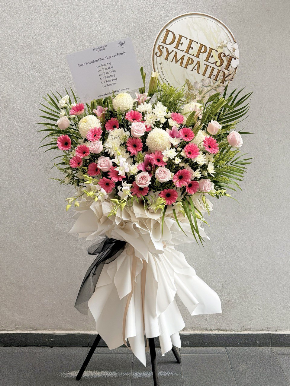 Floral arrangement with 'Deepest Sympathy' sign on a gray background prepared by Hug and Heart Florist Subang Jaya.