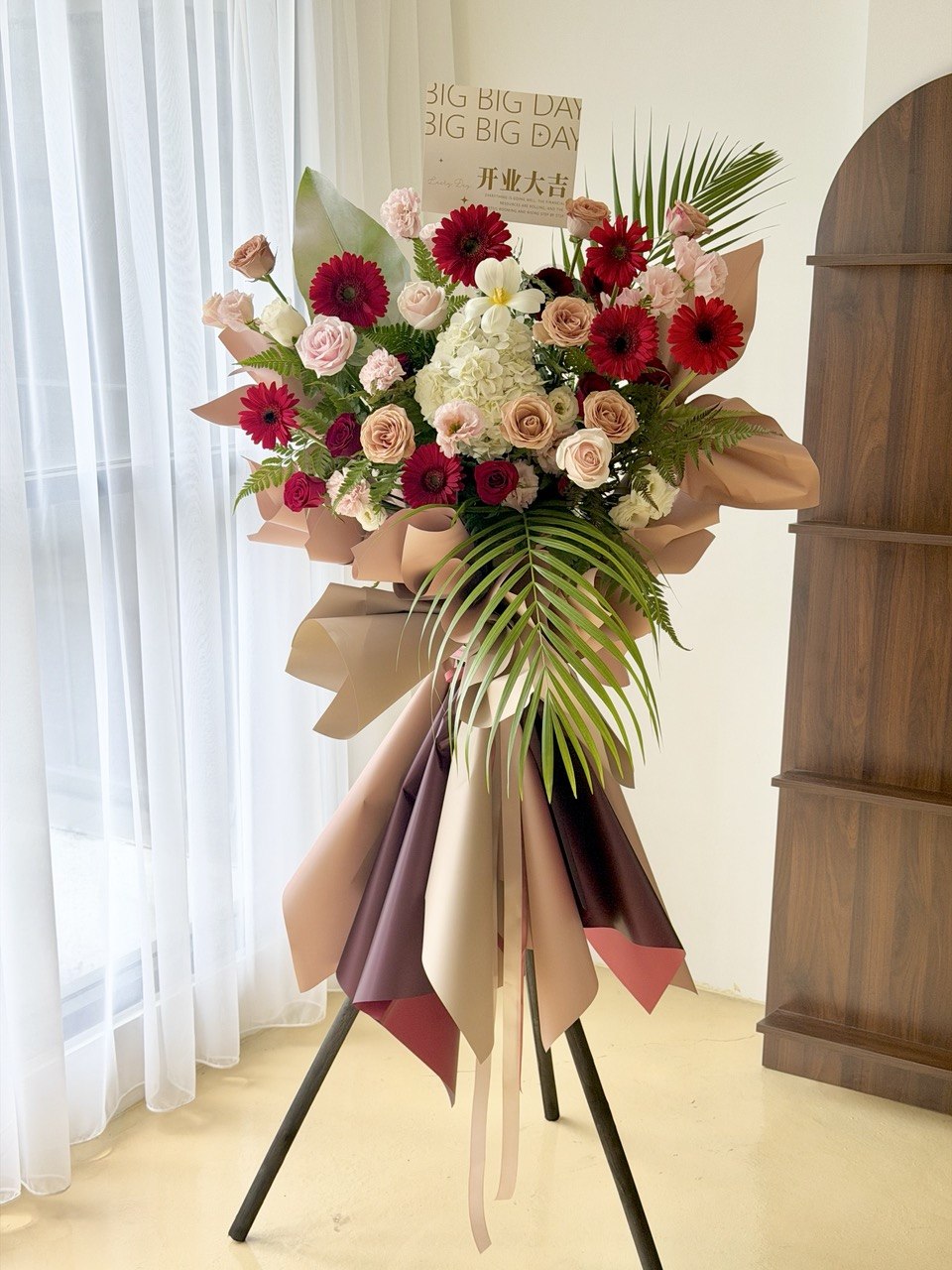Beautiful congratulation flower stand with red gerberas, champagne roses, white hydrangea and fresh seasonal flowers. Generous-sized grand opening flower stand by Hug and Heart Florist with same day delivery in KL and Selangor.