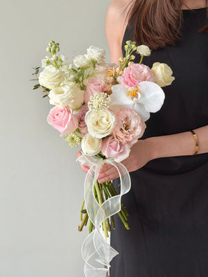 A girl wearing black dress is holding a bouquet of wedding ROM flower consists of pink roses, white roses, white phalaenopsis and some Eustoma with same day delivery at Kuala Lumpur and Selangor.