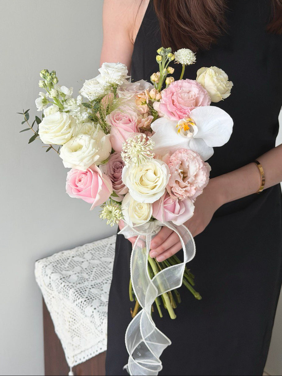 A girl wearing black dress is holding a bouquet of wedding ROM flower consists of pink roses, white roses, white phalaenopsis and some Eustoma with same day delivery at Kuala Lumpur and Selangor.