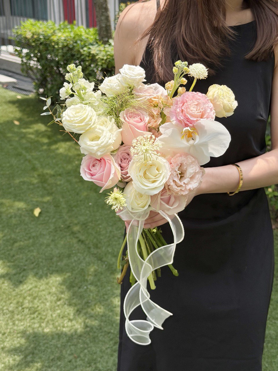 A girl wearing black dress is holding a bouquet of wedding ROM flower consists of pink roses, white roses, white phalaenopsis and some Eustoma with same day delivery at Kuala Lumpur and Selangor.