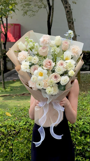 Romantic soft pastel bouquet arranged with Quicksand roses, white roses, white tulips, and seasonal flowers for anniversary, birthday, and apology flower gifting.