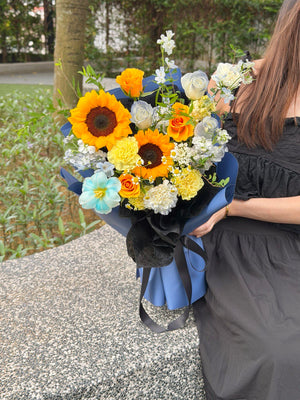 Elegant mixed-flower graduation bouquet with sunflowers, carnations, and blue roses for graduation celebration.