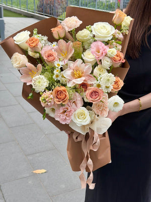 A girl is holding a cappuccino flower bouquet with cappuccino roses, champagne dyed tulips, white roses and seasonal flowers for same day florist delivery in KL and Selangor.