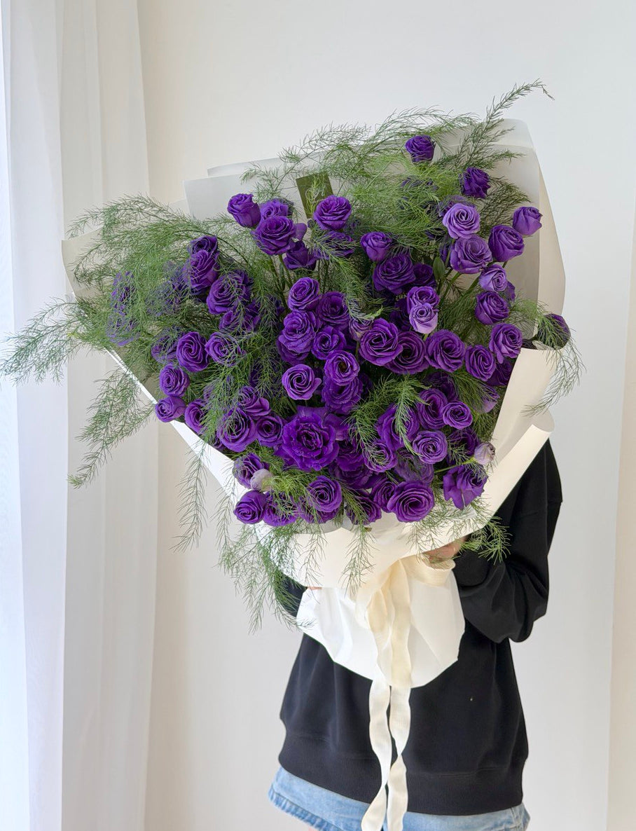 Person holding a large bouquet of purple Eustoma flowers outdoors perfect for birthday celebration at Kuala Lumpur.