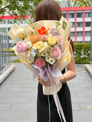 A woman from behind holding a large, colorful bouquet of flowers wrapped in cream paper, flower bouquet kl.