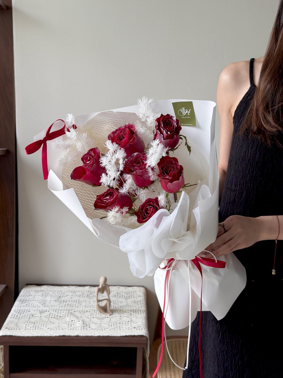 Person holding a bouquet of red roses and white flowers wrapped in white paper with a red ribbon perfect for this Christmas flower gift.
