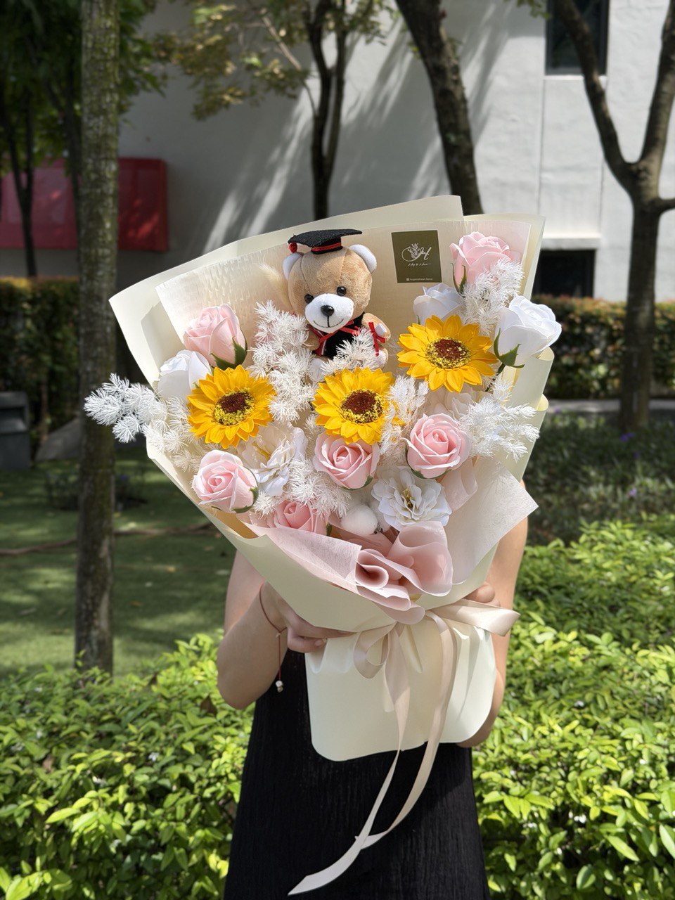 A sunflower soap flower with pink soap flower, white soap flower and one graduation bear ready for graduation flower gift.