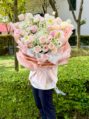 Person holding a large bouquet of flowers outdoors for birthday celebration. 