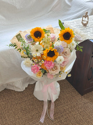 Bouquet of flowers with sunflowers and other flowers on a carpeted floor.