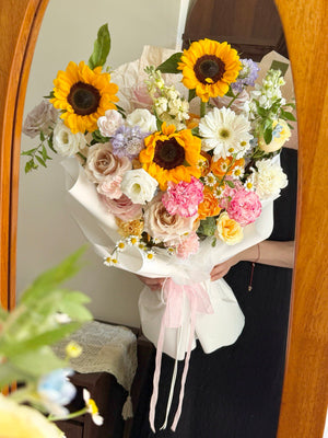 A girl is standing infront of a mirror holding her graduation sunflower bouquet.