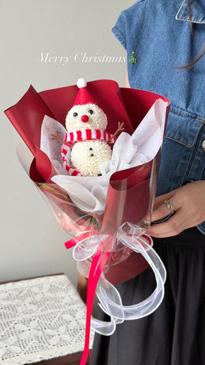 Bouquet with a snowman decoration and red ribbon, held by a person wearing a denim jacket.