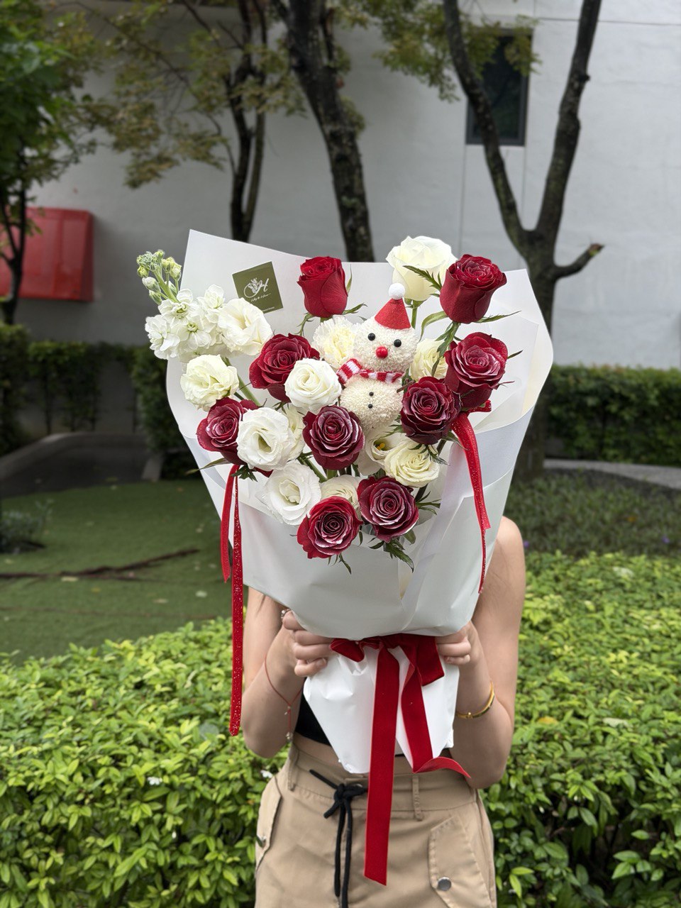 A bouquet of Christmas flower bouquet with a ping pong snow man held by a girl outdoor, perfect for Christmas gift. 