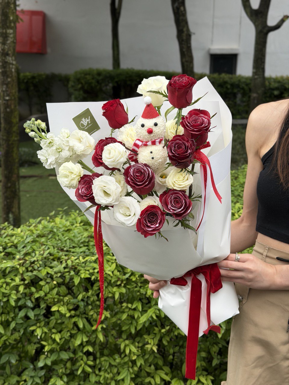 A bouquet of red rose and white eustoma with a snow man figure perfect for Christmas gift at Kuala Lumpur.