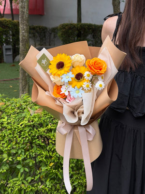 A girl is holding a bouquet of soap flower with soap flower sunflower for her graduation at University.