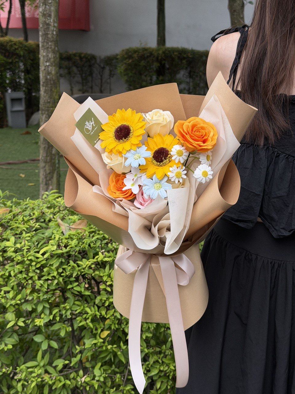 A girl is holding a bouquet of soap flower with soap flower sunflower for her graduation at University.