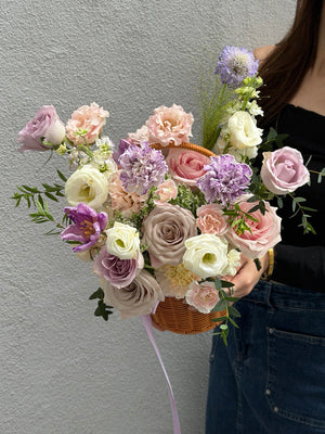 Purple pastel flower basket with roses, purple tulip, menta roses, lilac roses and purple carnation designed as a get well soon flower arrangement to send comfort and warm wishes.